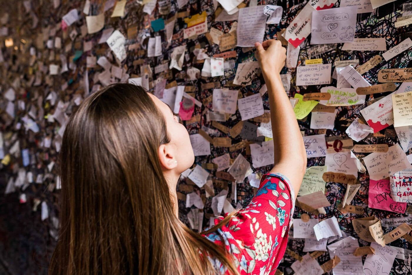 A visitor leaving a note on the wall of letters at Juliet's House in Verona